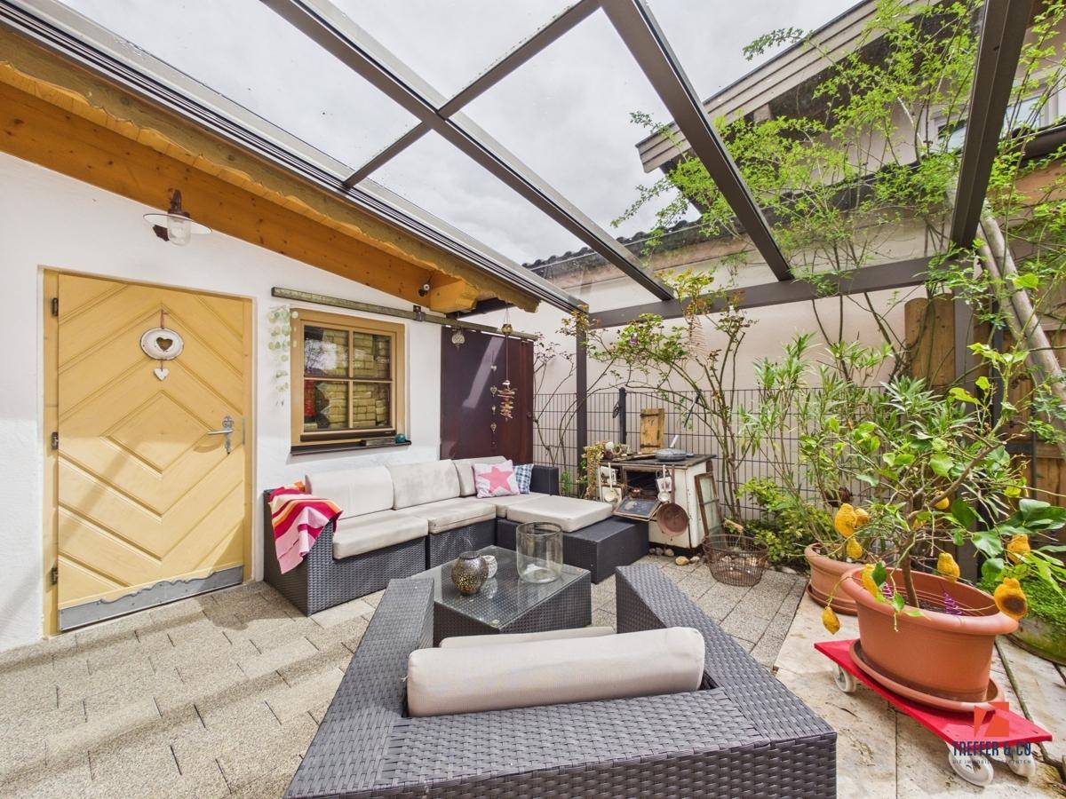 Überdachte Terrasse mit moderner Lounge-Sitzgruppe, Glasdach und Topfpflanzen für gemütliche Stunden.