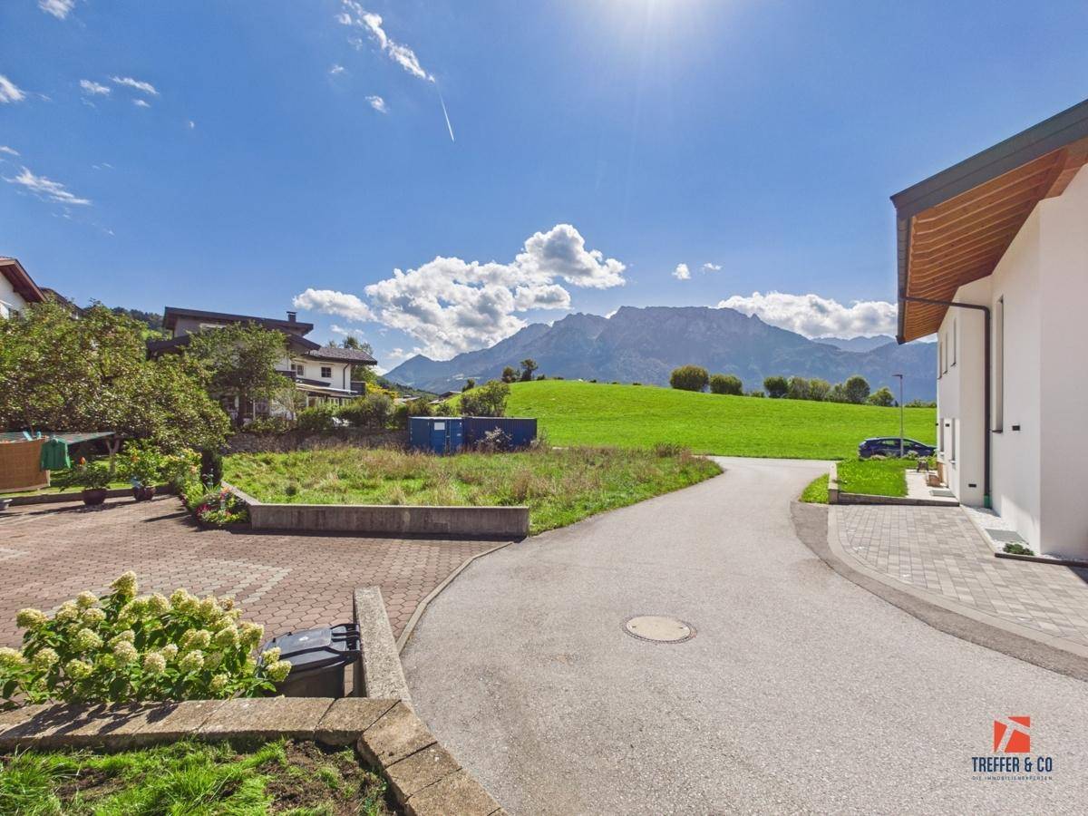 Malerische Umgebung mit grünen Wiesen, Bergen und einem sonnigen Himmel.