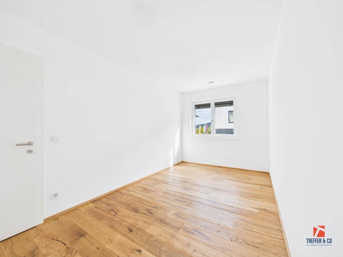 Helles Schlafzimmer mit Holzboden und Fenster, ideal als Kinder- oder Gästezimmer.