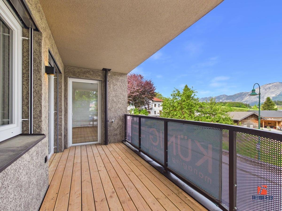 Breiter Balkon mit Holzboden und Zugang zum Innenbereich, bietet Bergblick.