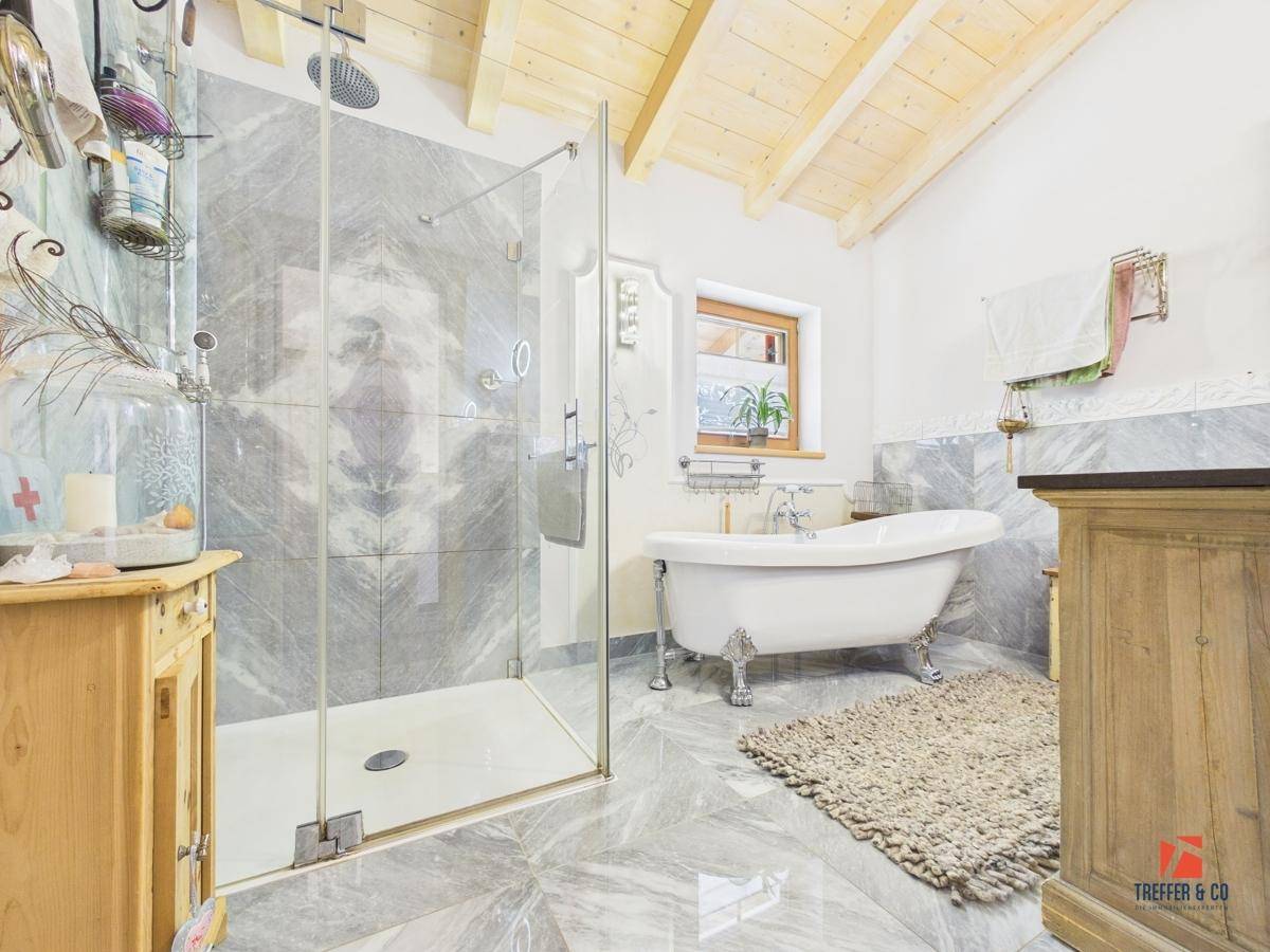 Modernes Badezimmer mit freistehender Badewanne, begehbarer Dusche und Holzbalkendecke.