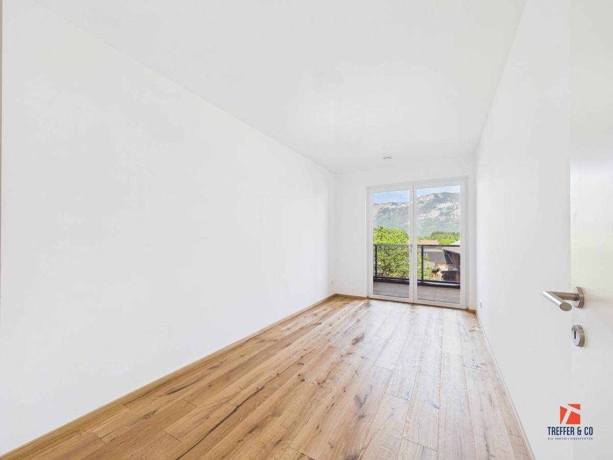 Helles Schlafzimmer mit Holzboden und Balkonzugang, bietet einen schönen Bergblick.
