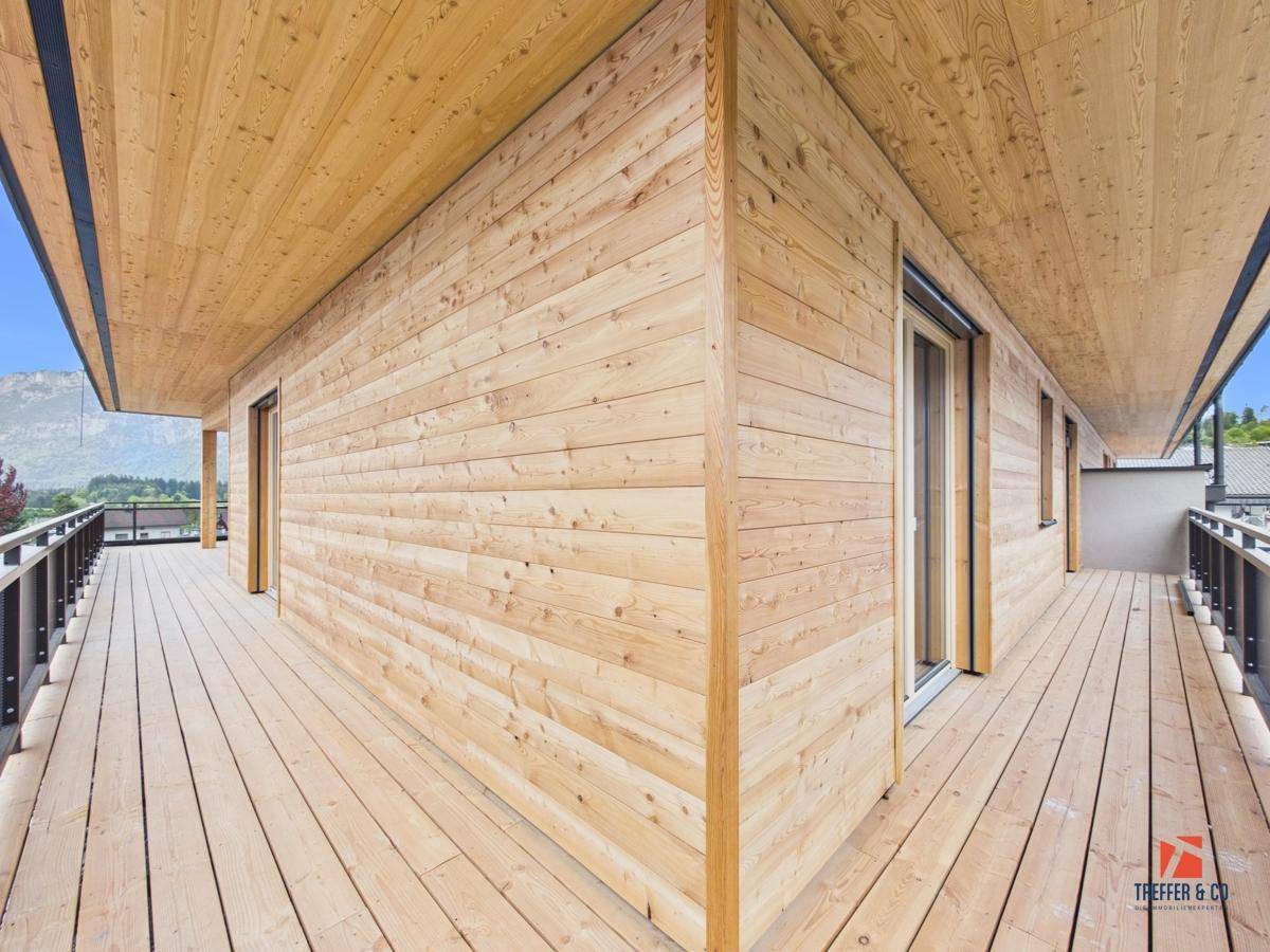 Langer Holzbalkon mit Holzverkleidung und Blick auf die umliegende Berglandschaft.