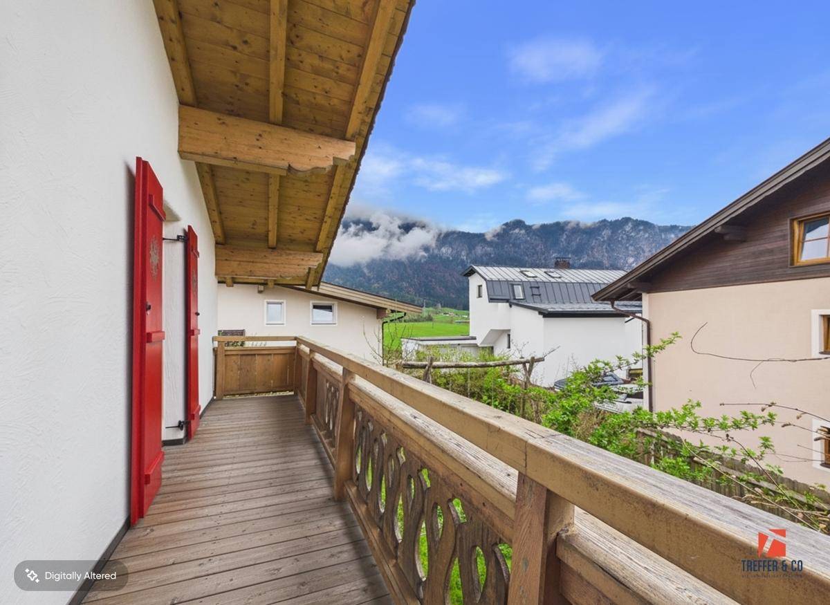 Holzbalkon mit traditionellem Geländer und Blick auf die umliegende Berglandschaft.