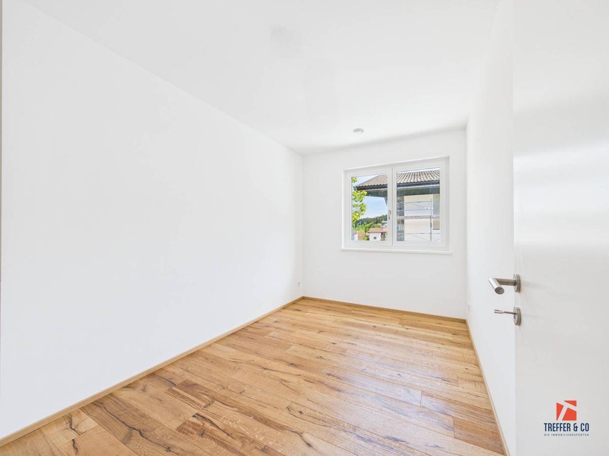 Leeres Zimmer mit Holzboden und Fenster, bietet viel natürliches Licht.