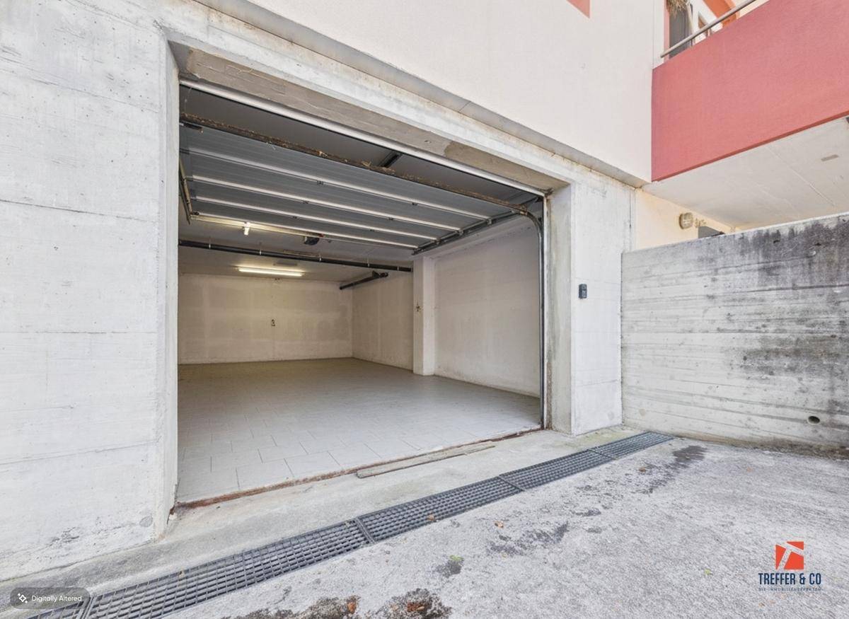 Außenansicht einer Garage mit Betonwänden und Entwässerungsrinne vor dem Eingang.