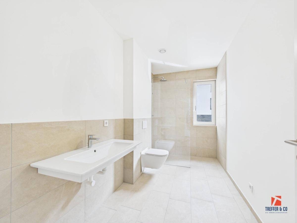 Modernes Badezimmer mit großem Waschbecken, begehbarer Dusche und Fenster.