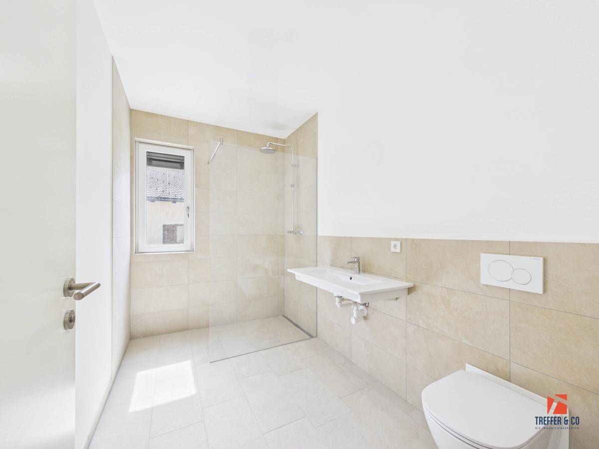 Modernes Badezimmer mit begehbarer Dusche, Wand-WC und hellen Fliesen.