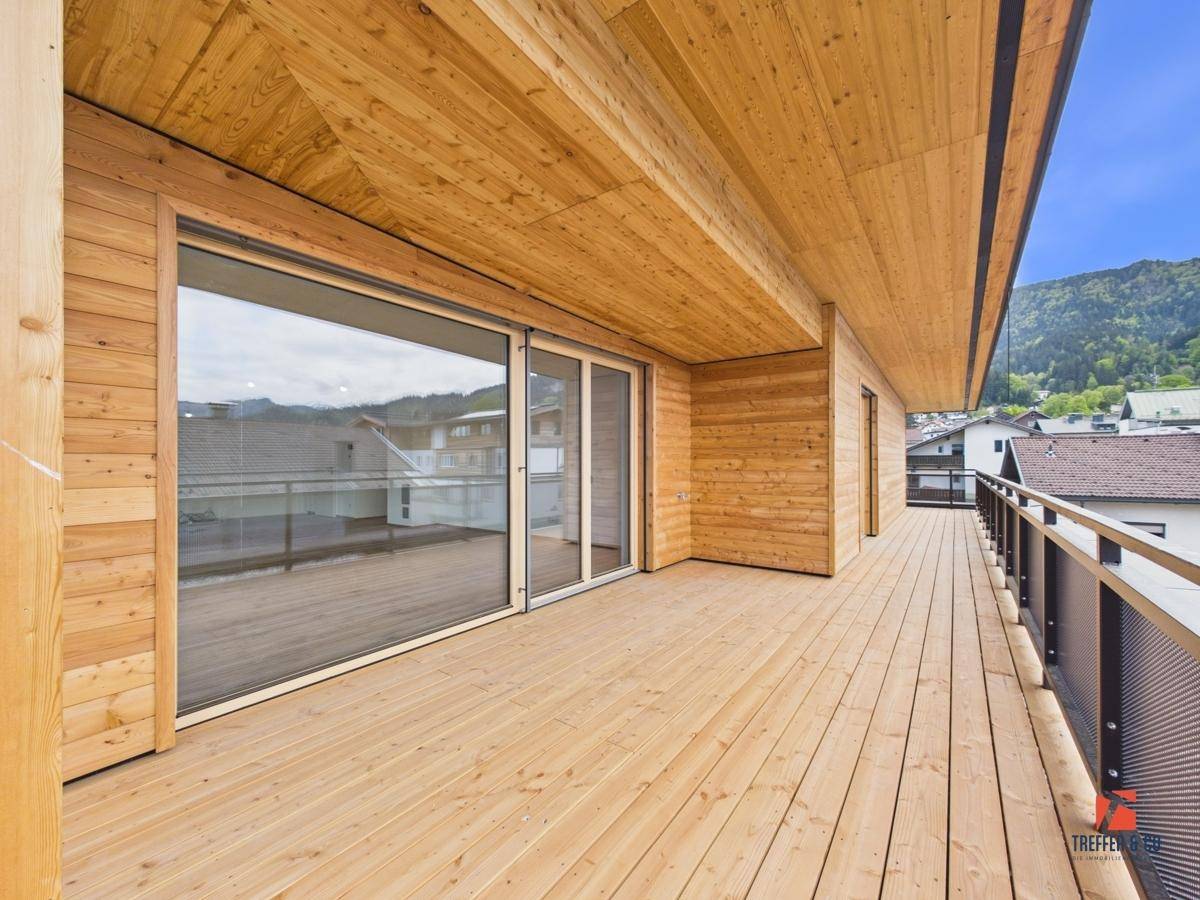 Geräumiger Holzbalkon mit Holzfassade und Blick auf die umliegende Landschaft.