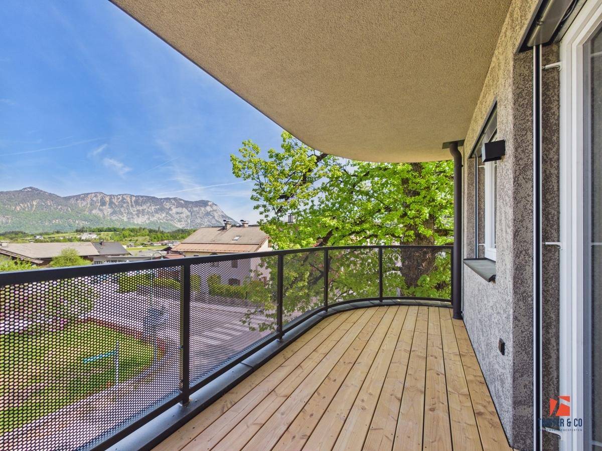 Geräumiger Balkon mit Holzboden und Metallgeländer, bietet einen weiten Bergblick.