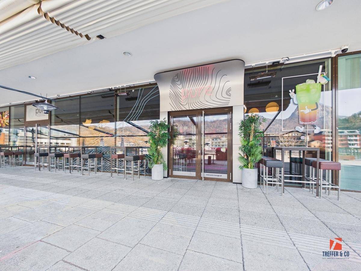 Moderne Lounge-Terrasse mit stilvollen Barhockern und einem weiten Blick auf die Landschaft und Berge.