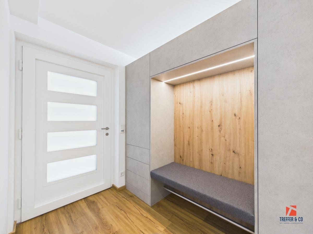 Detailansicht des modernen Eingangsbereichs mit beleuchteter Sitzbank und stilvoller Garderobe.
