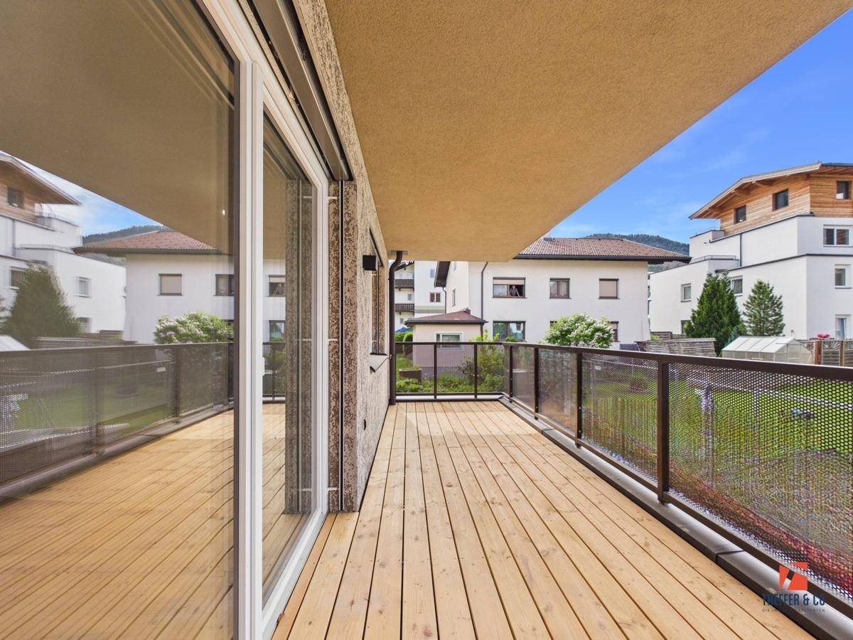 Geräumiger Holzbalkon mit Metallgeländer und Blick auf die umliegende Wohngegend.