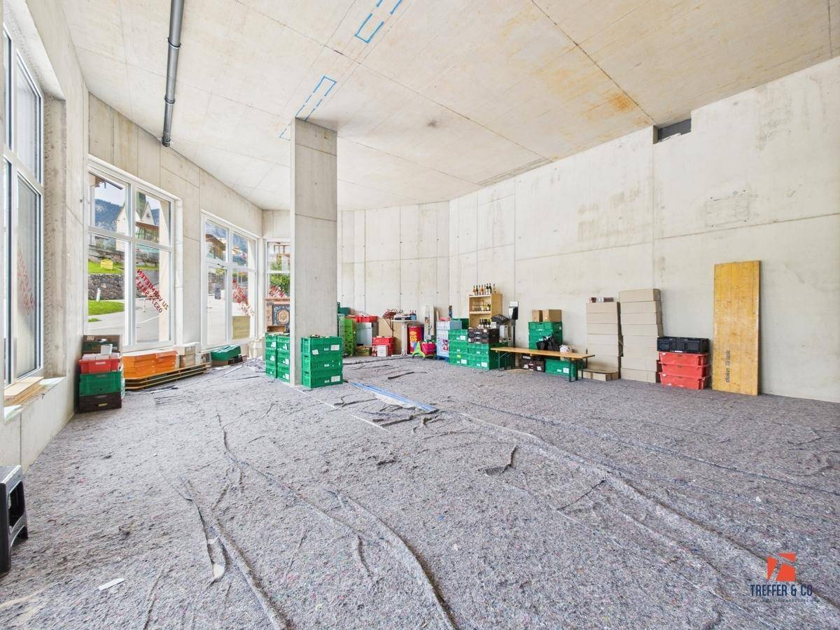 Weitläufiger, unfertiger Raum mit Sichtbetonwänden und -decke, bereit für den Innenausbau.