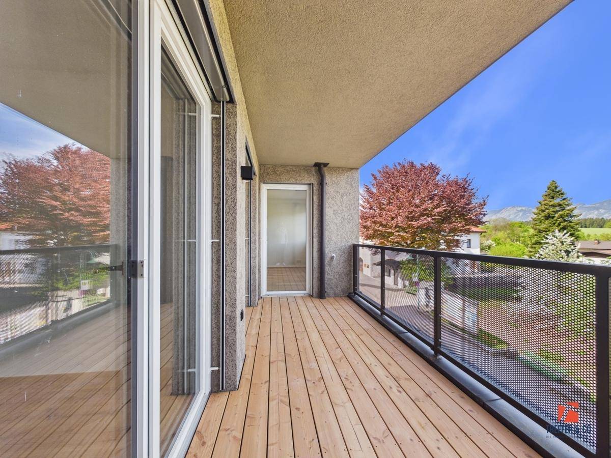 Heller Balkon mit Holzboden und modernem Geländer, ideal zum Entspannen im Freien.