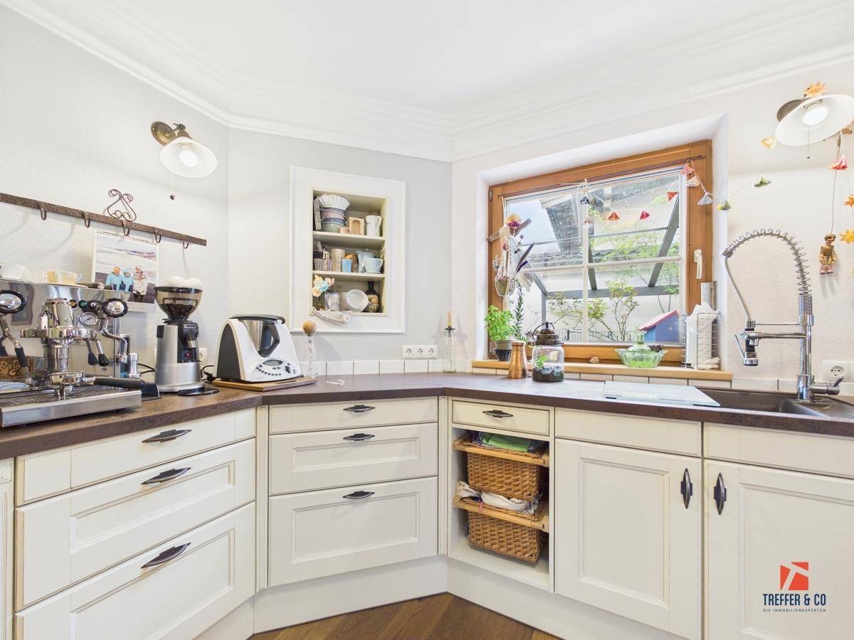 Detailansicht der Landhausküche mit Spülbecken, Kaffeemaschine und einem Fenster über der Arbeitsplatte.