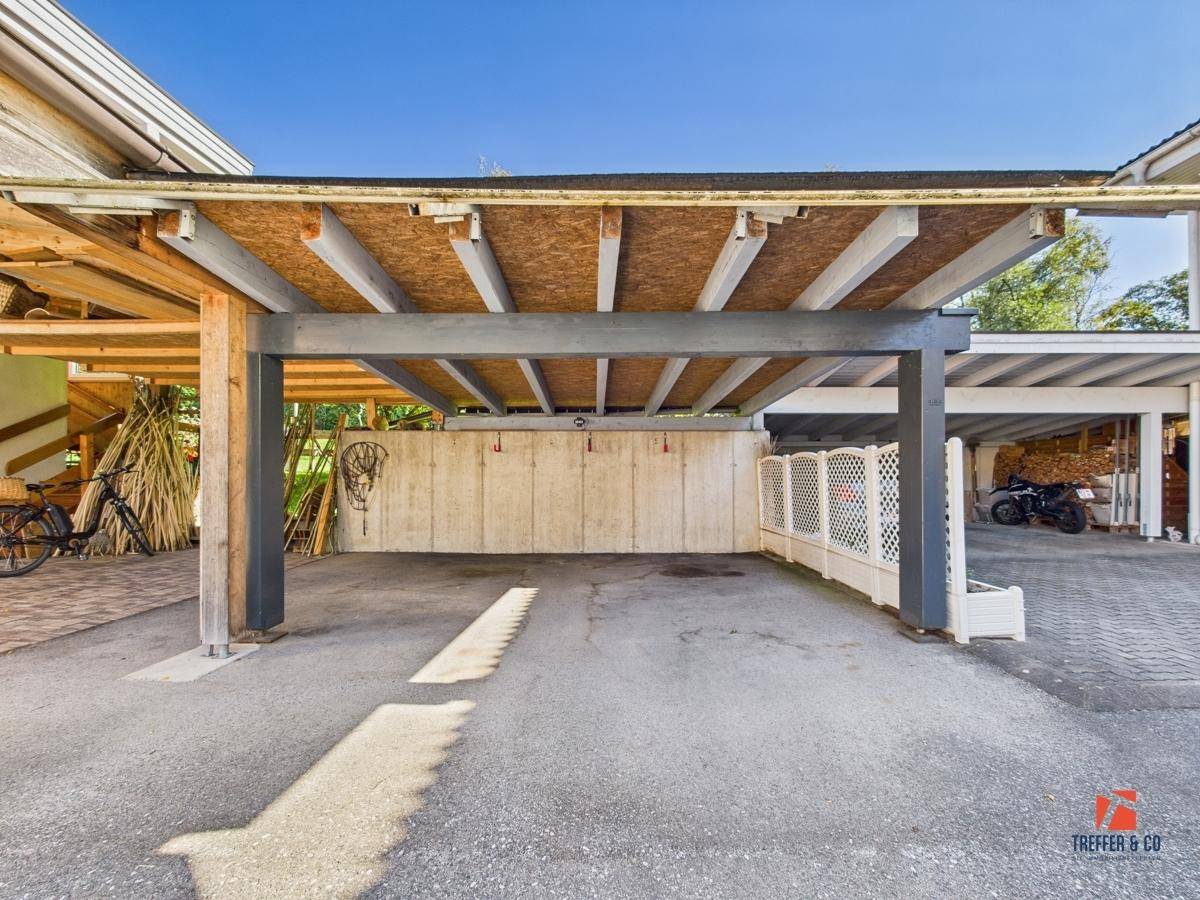 Überdachter Parkplatz oder Carport mit Betonwand und Blick auf weitere Stellplätze.