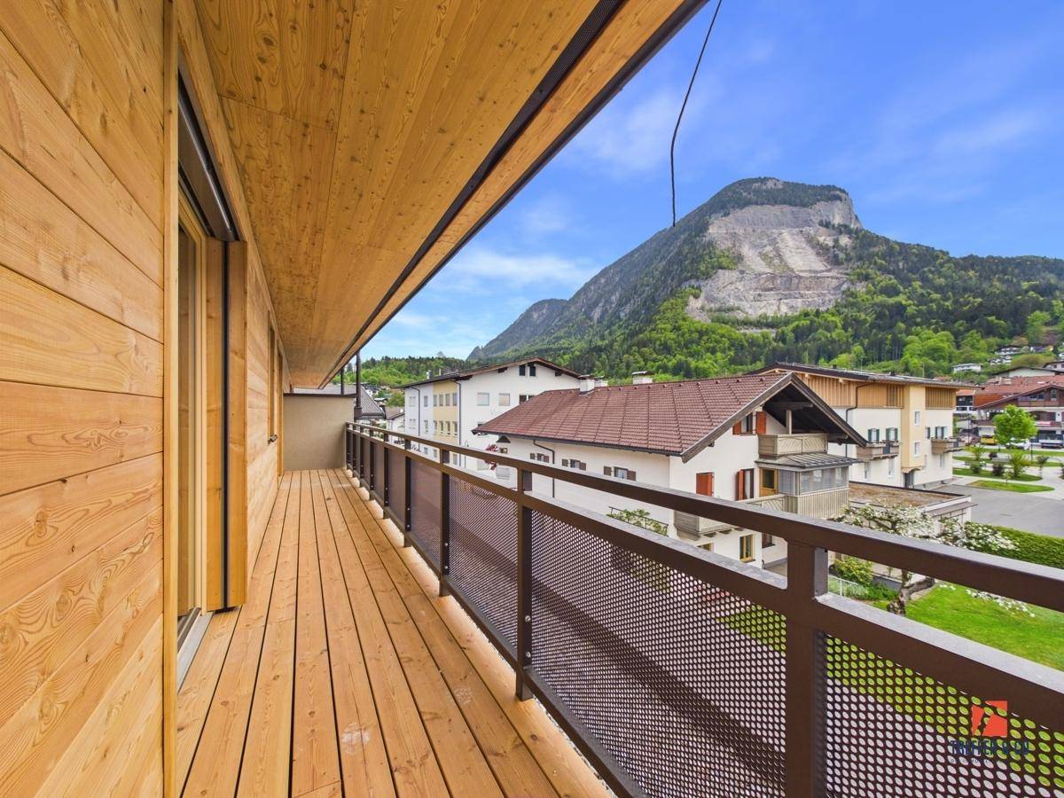 Geräumiger Balkon mit Holzboden und moderner Brüstung, bietet einen weiten Blick auf die Berge.
