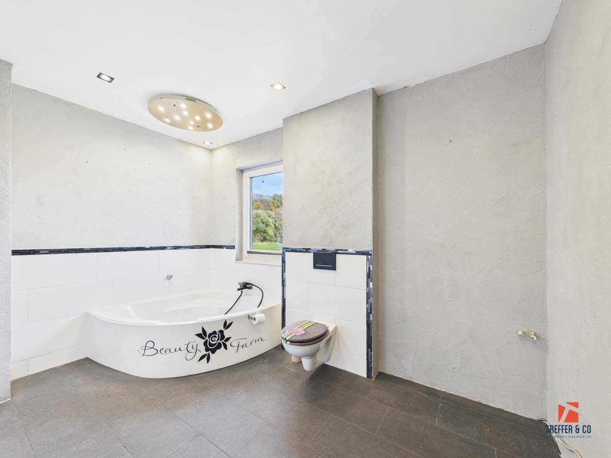 Geräumiges Badezimmer mit Eckbadewanne, Wand-WC und Fenster.