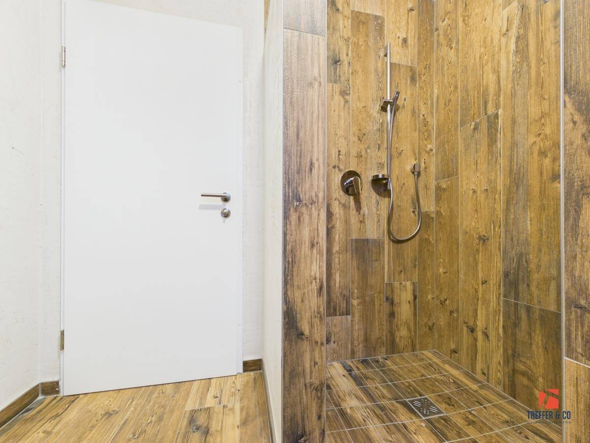 Begehbare Dusche mit stilvollen Holzoptik-Fliesen und modernen Armaturen.