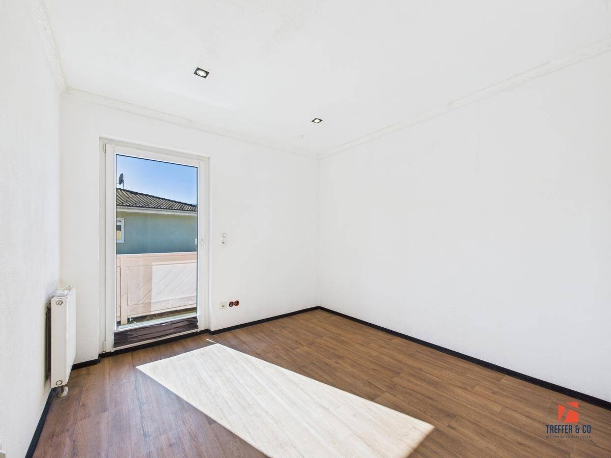 Helles Zimmer mit Laminatboden und Zugang zu einem französischen Balkon.