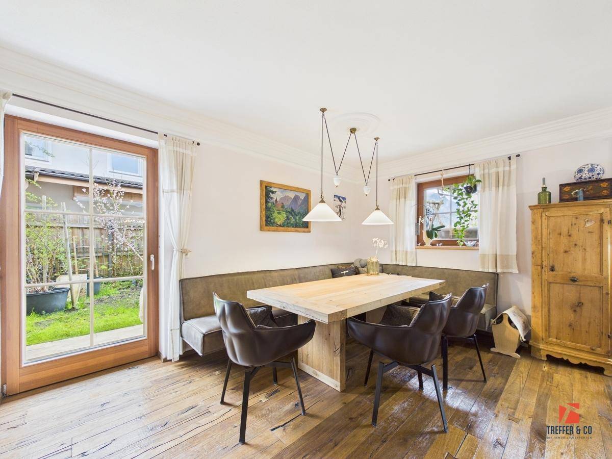 Essbereich mit Holzboden und direktem Zugang zum Garten durch eine große Fenstertür.