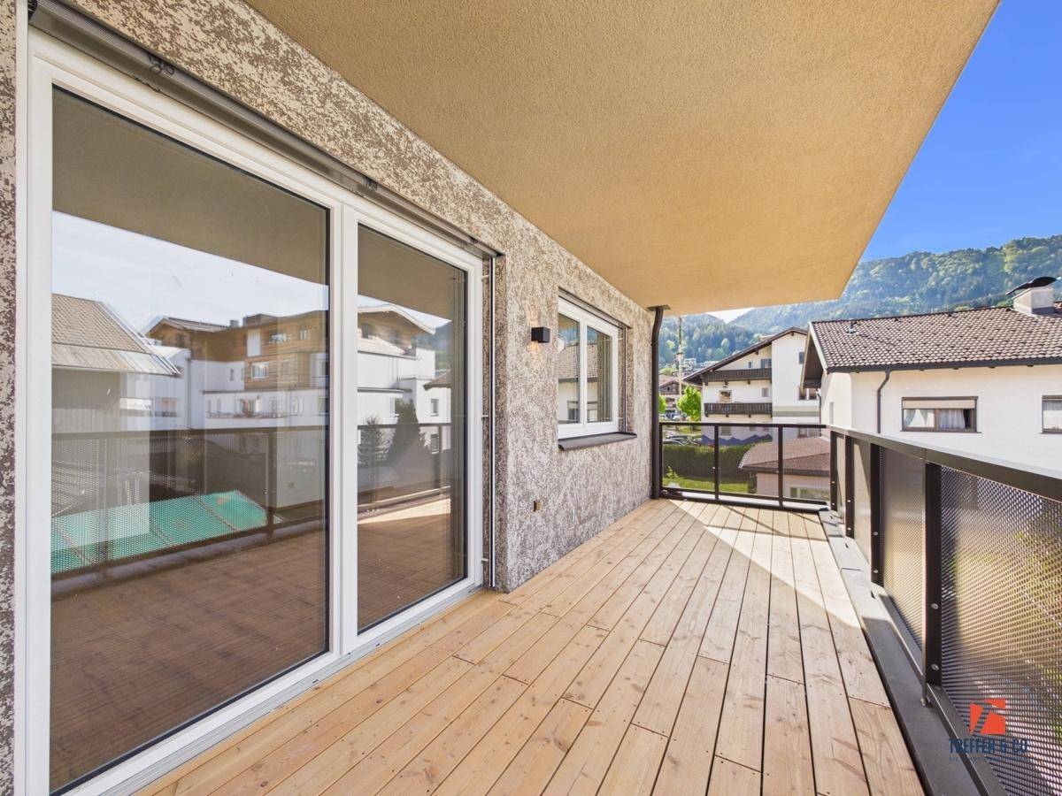 Breiter Balkon mit Holzdielen und modernem Geländer, bietet weite Aussicht.