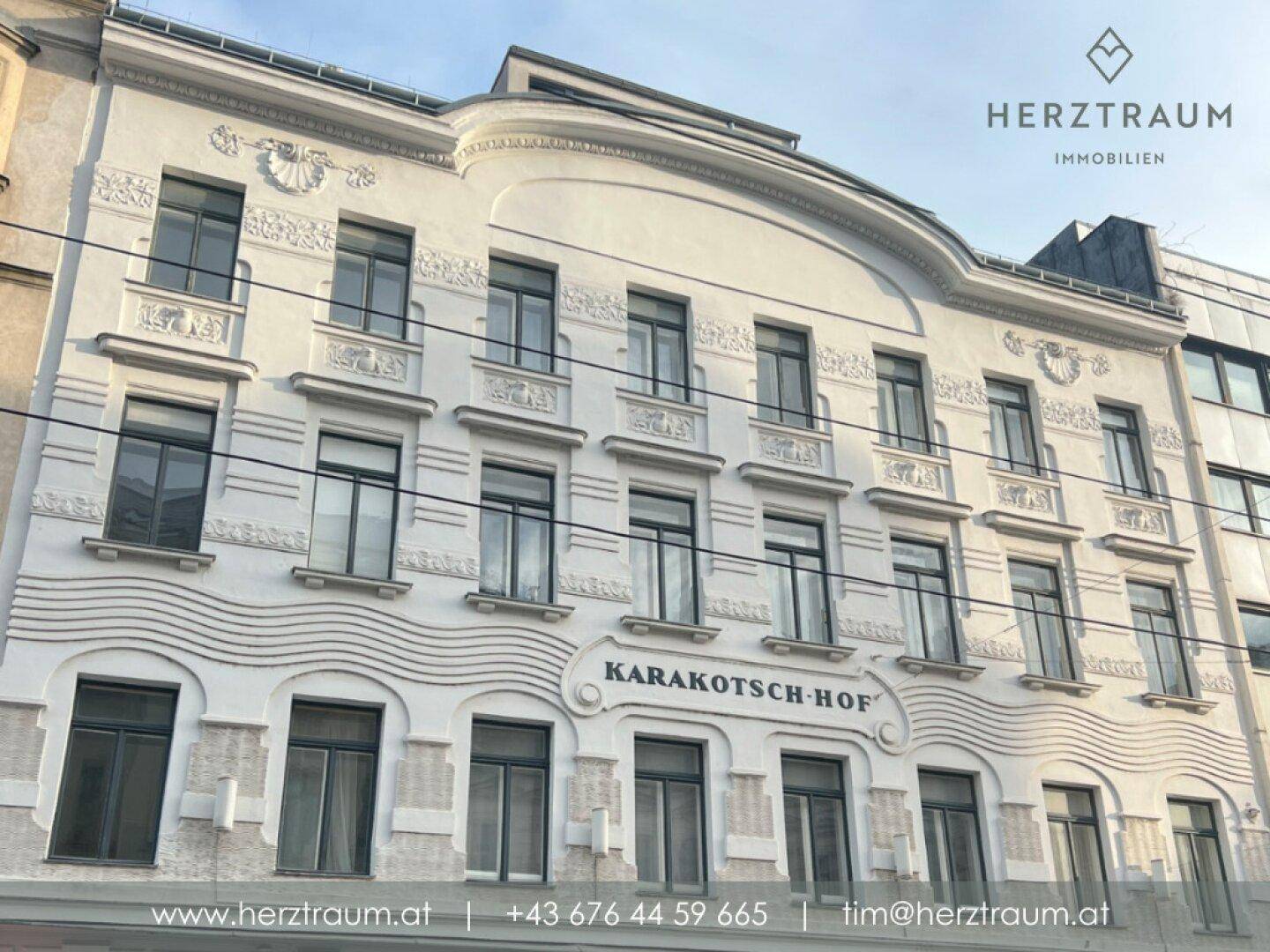 Historische Gebäudefassade des Karakotsch-Hofs mit kunstvollen Verzierungen und großen Fenstern.