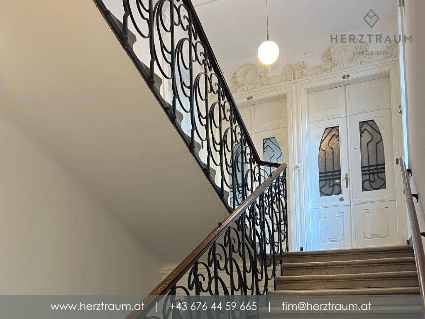 Elegantes Treppenhaus mit kunstvollem schmiedeeisernem Geländer und Stuckverzierungen.