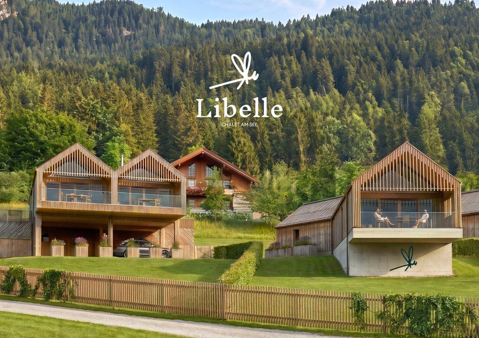 Moderne Chalets mit Holzfassaden und Glasbalkonen, eingebettet in eine grüne Berglandschaft mit Wald.