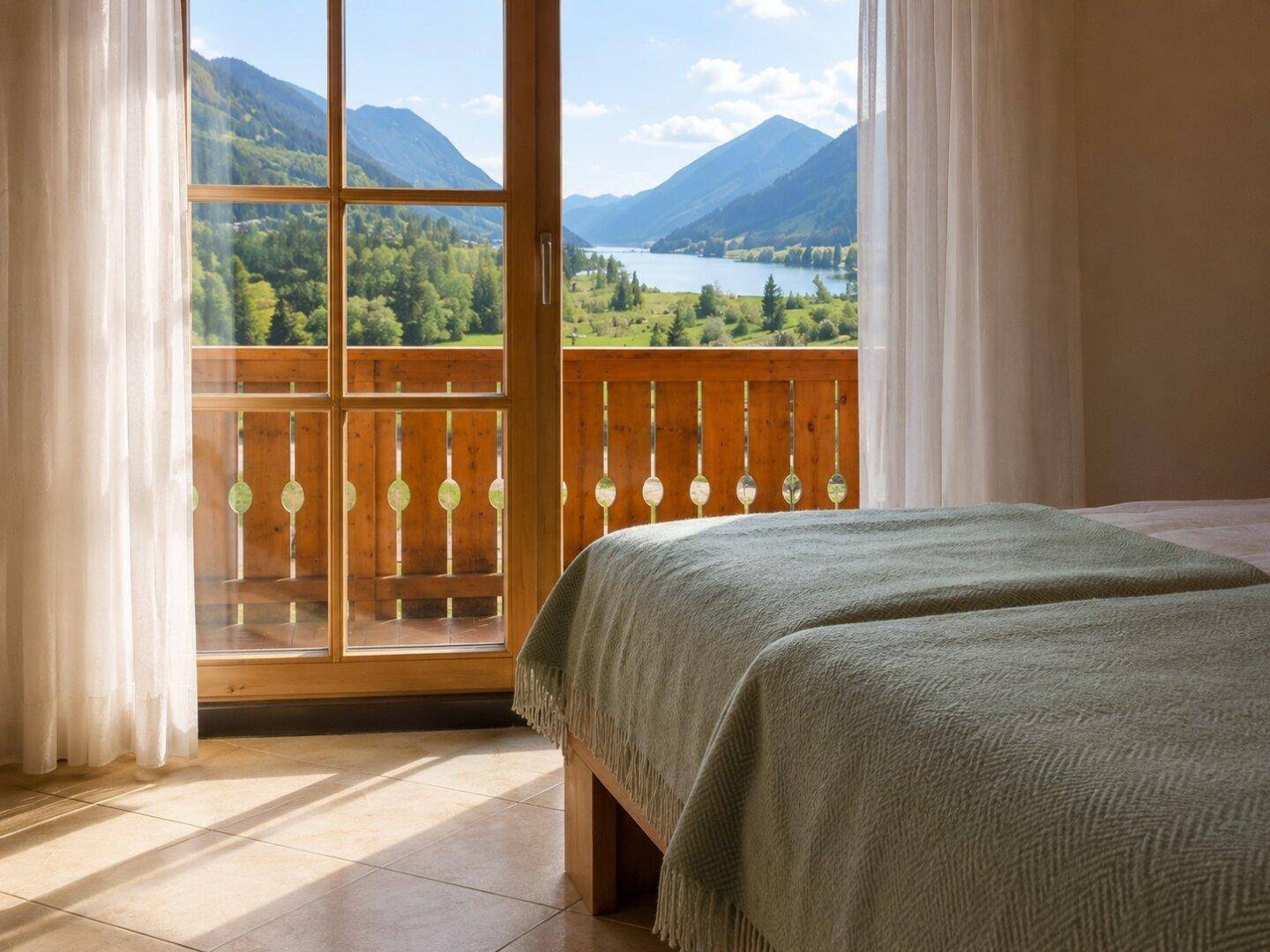 Schlafzimmer mit Balkonzugang und malerischem Blick auf den See und die umliegende Berglandschaft.
