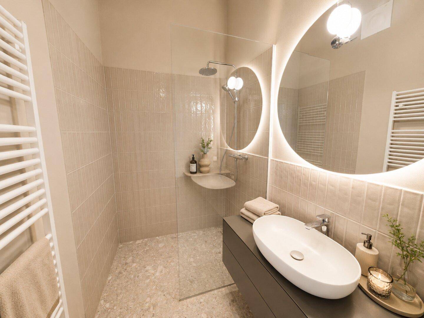 Modernes Badezimmer mit begehbarer Dusche, beleuchtetem Spiegel und beheiztem Handtuchhalter.