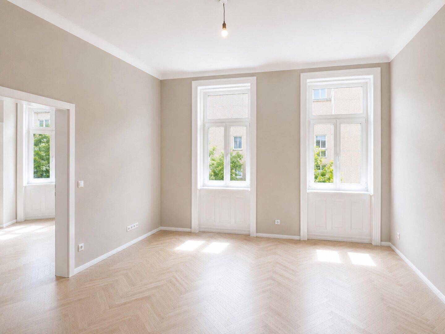 Heller Wohnraum mit Fischgrätparkett und hohen Fenstern, die den Blick auf die Umgebung freigeben.