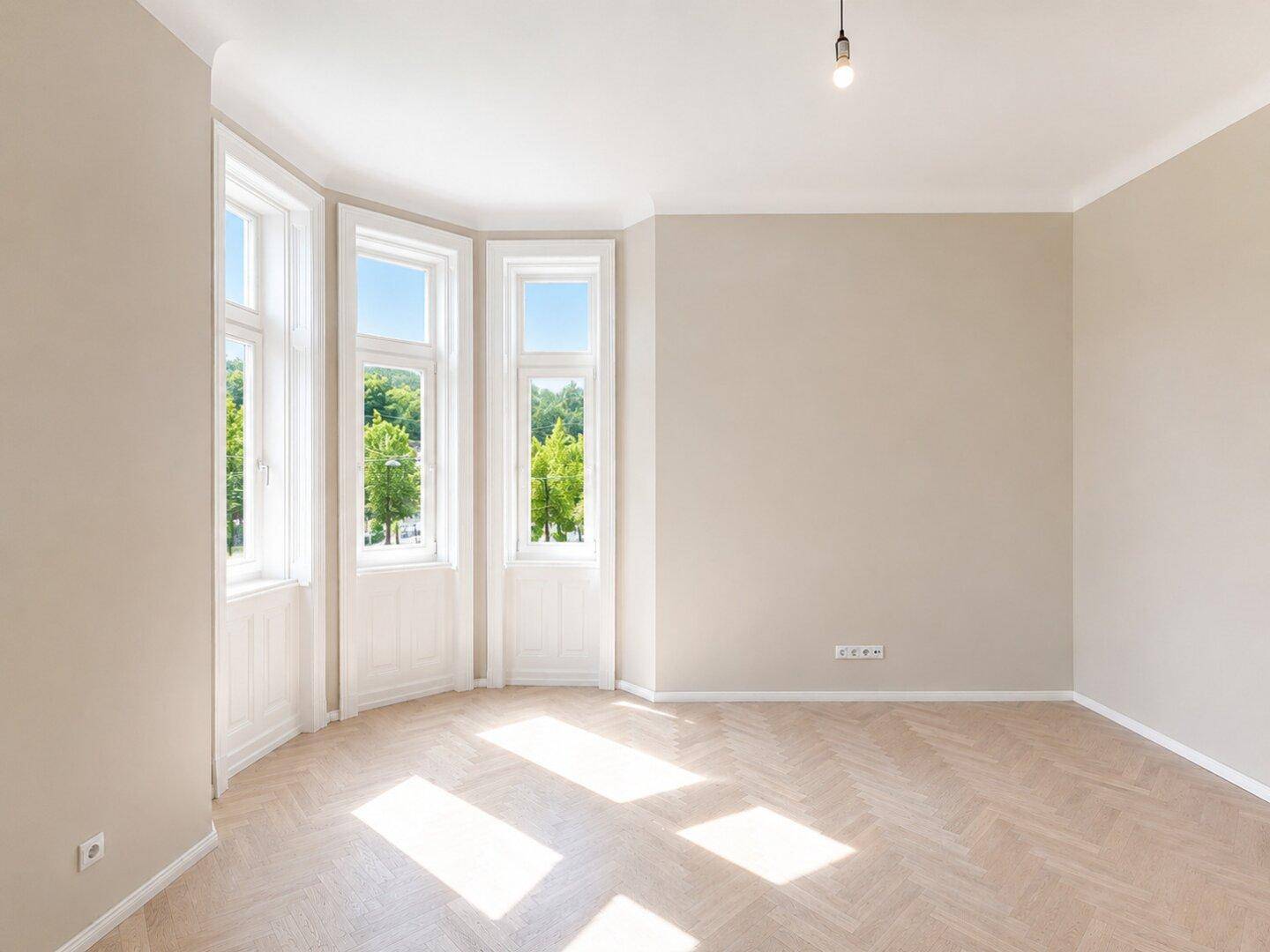 Lichtdurchflutetes Wohnzimmer mit Fischgrätparkett und großen Fenstern, die einen grünen Ausblick bieten.
