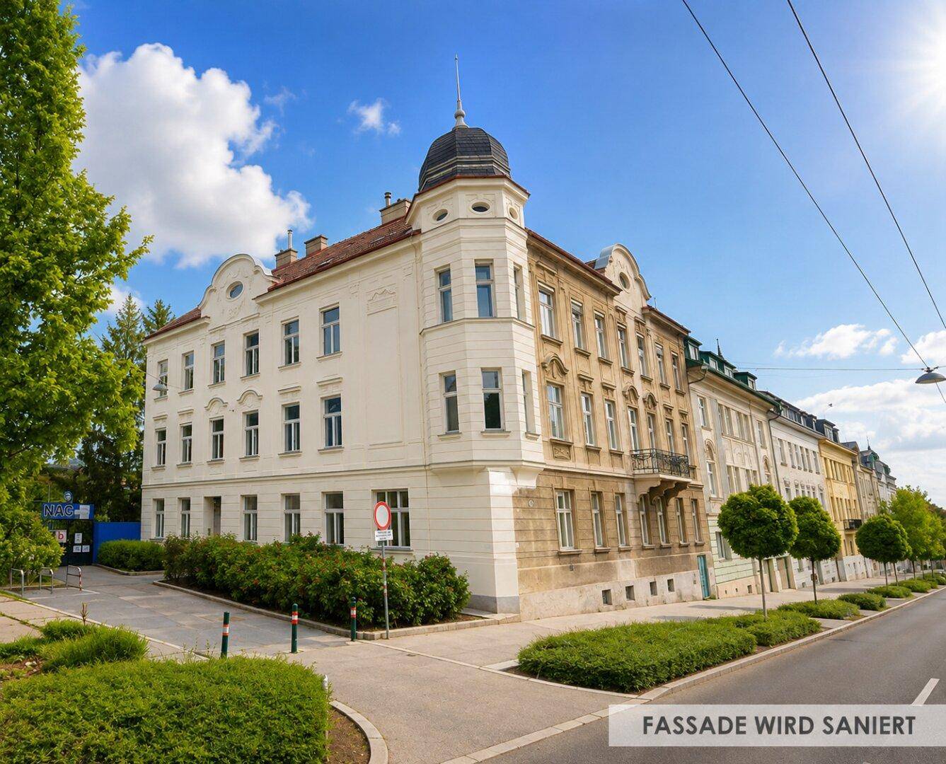 Historisches Eckgebäude mit sanierter Fassade an einer belebten Straße unter blauem Himmel.