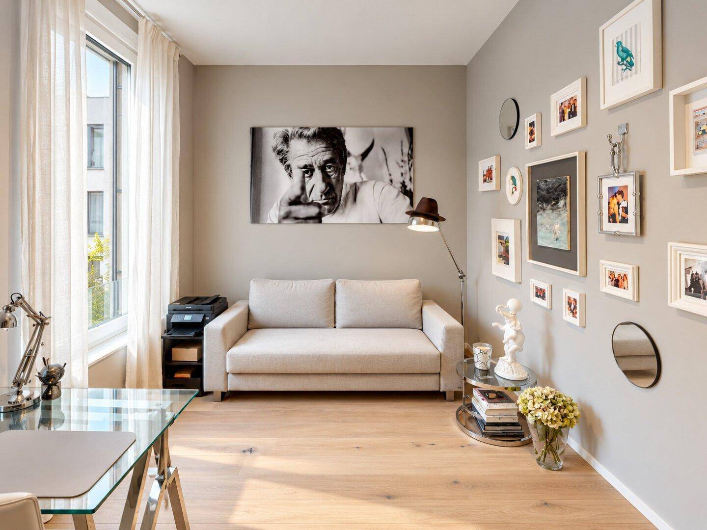 Ruhiges Arbeitszimmer mit Schreibtisch, Sofa, Parkettboden und großem Fenster für viel Tageslicht.