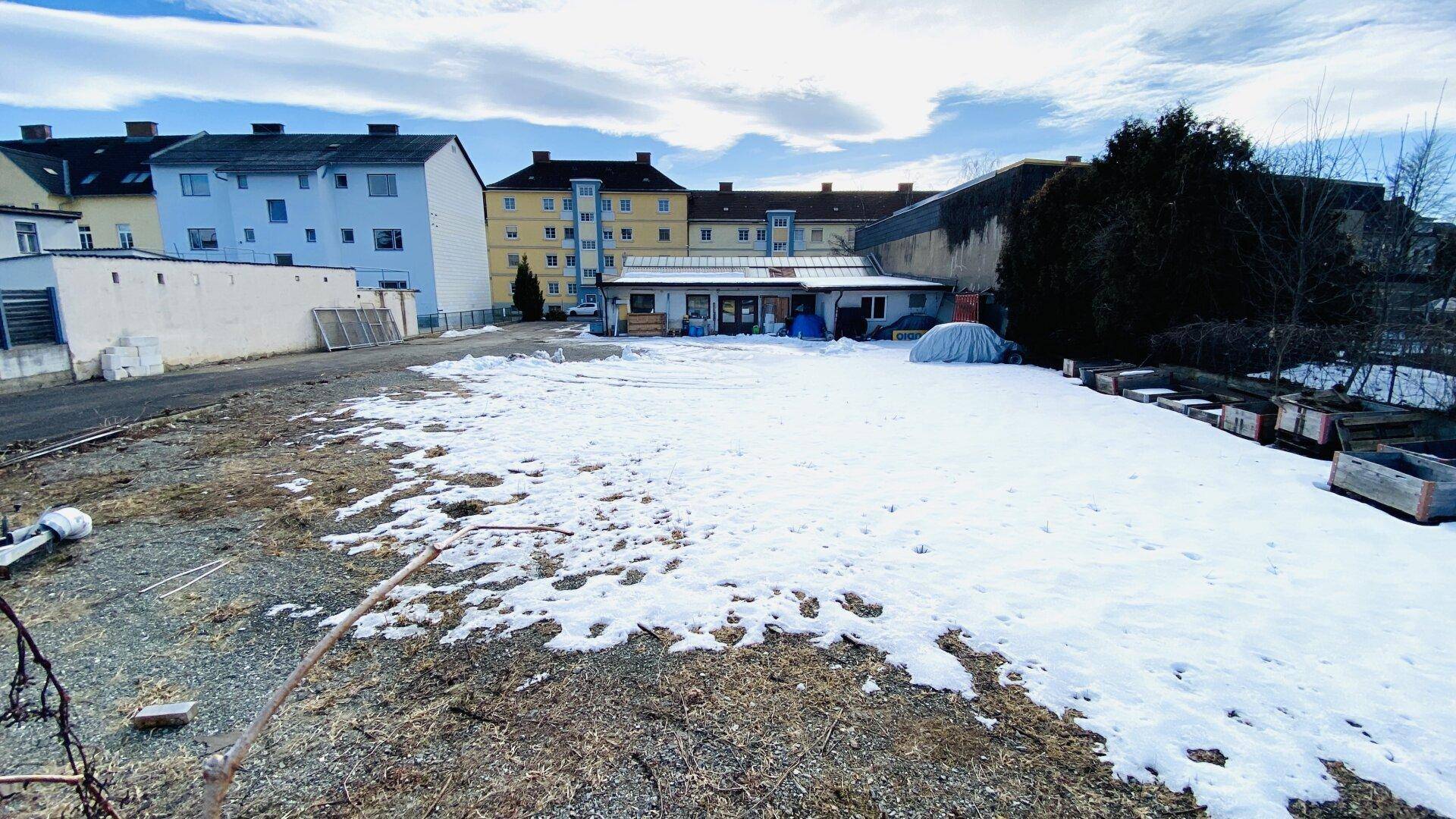 Großes, teilweise schneebedecktes Grundstück mit Blick auf angrenzende Wohn- und Gewerbegebäude.