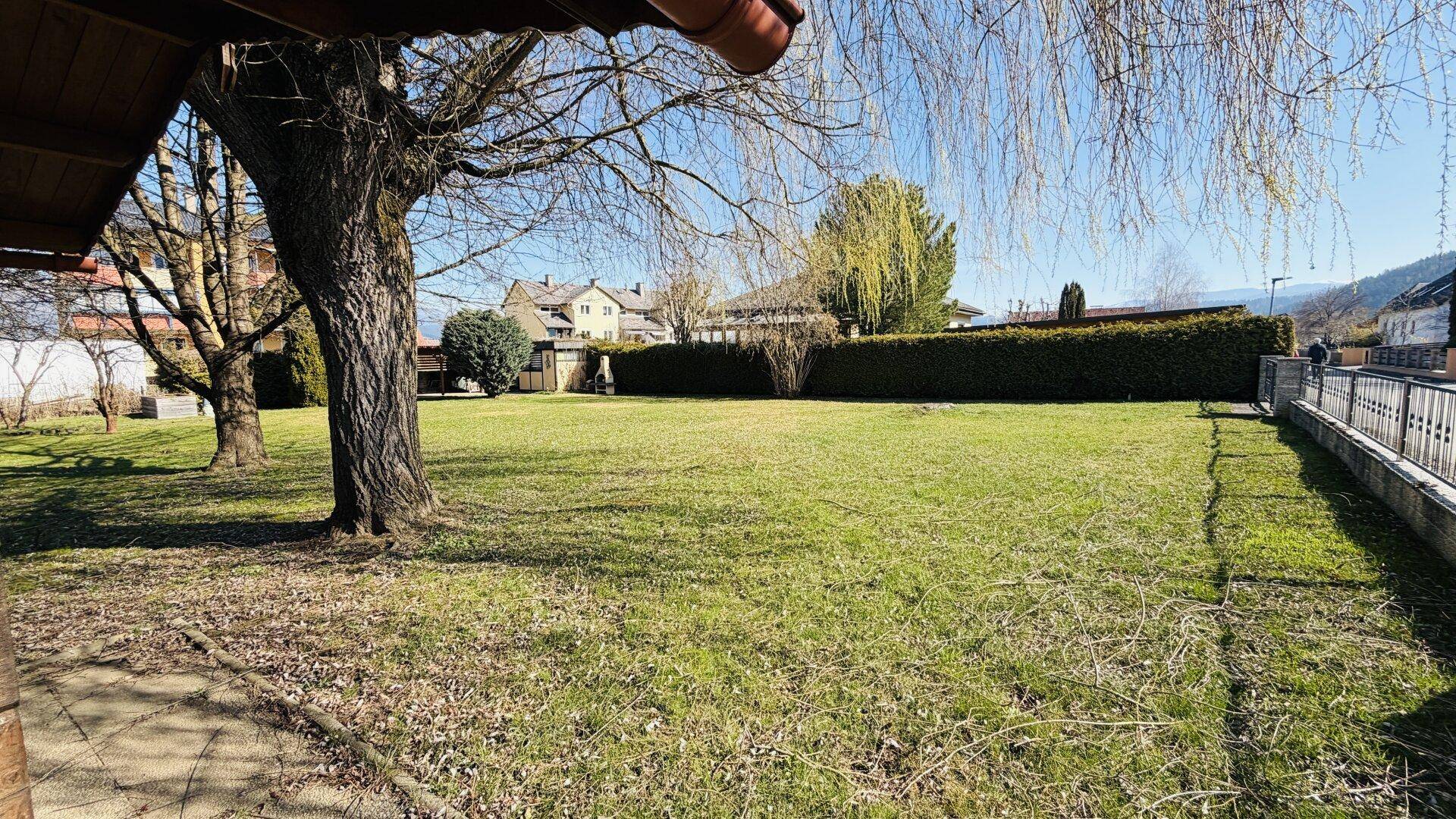 Weitläufiger Gartenbereich mit einem Zaun im Vordergrund und viel Grünfläche.
