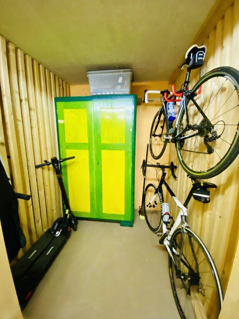 Abstellraum mit Holzverkleidung, Fahrrädern und einem grünen Schrank.