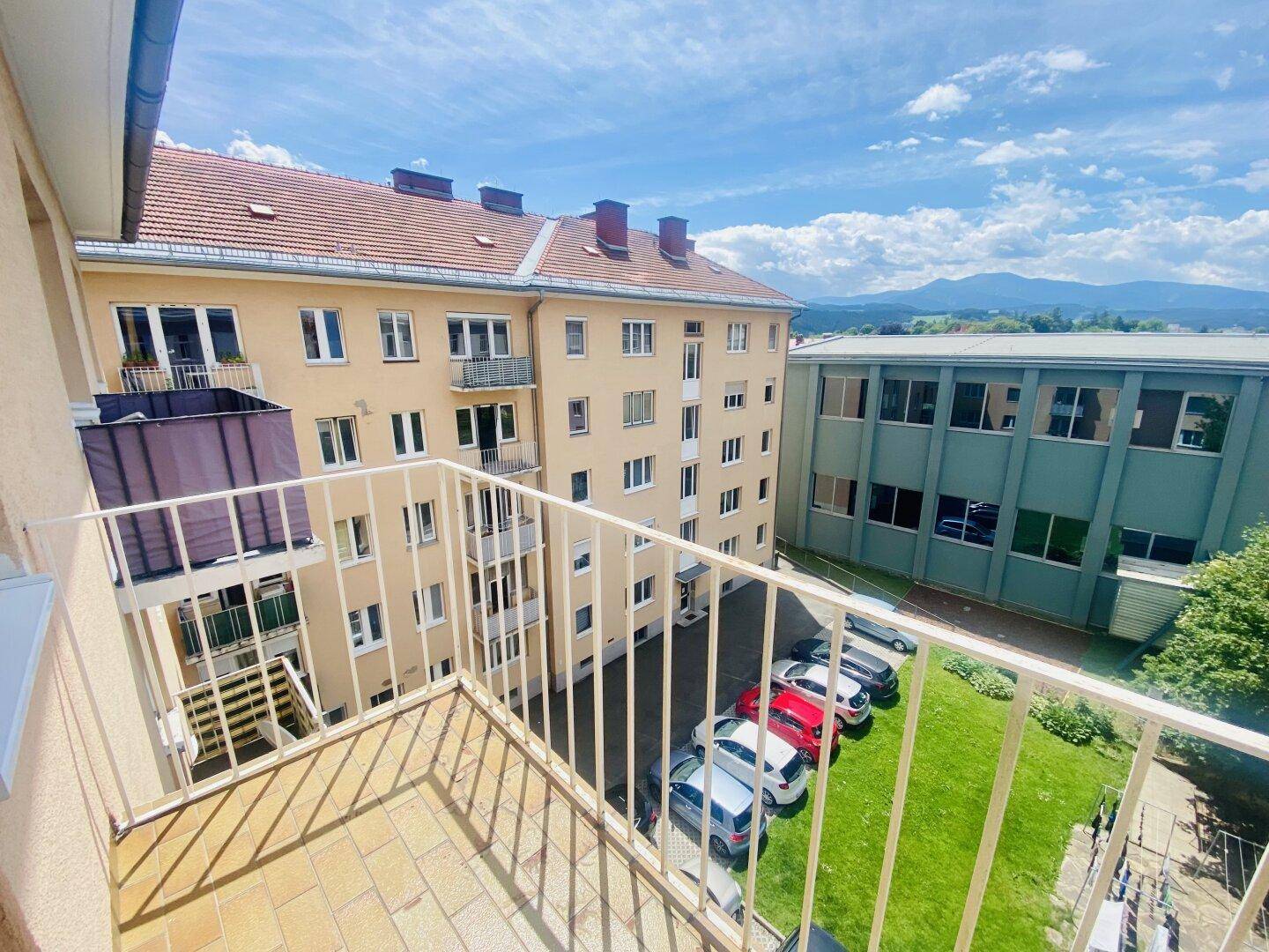 Balkon mit Weitblick über den Innenhof, umliegende Häuser und die Bergkette.