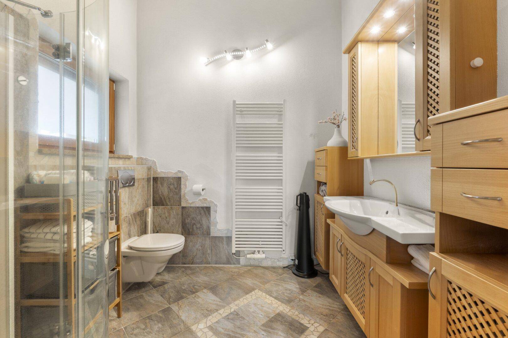 Modernes Badezimmer mit Doppelwaschbecken, Dusche und beheiztem Handtuchhalter.