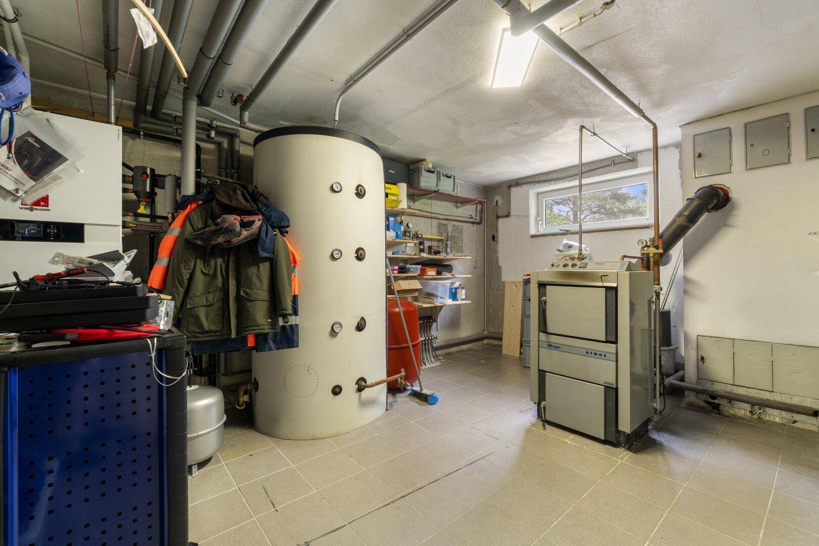 Technikraum im Keller mit Heizungsanlage, Warmwasserspeicher und gefliestem Boden.