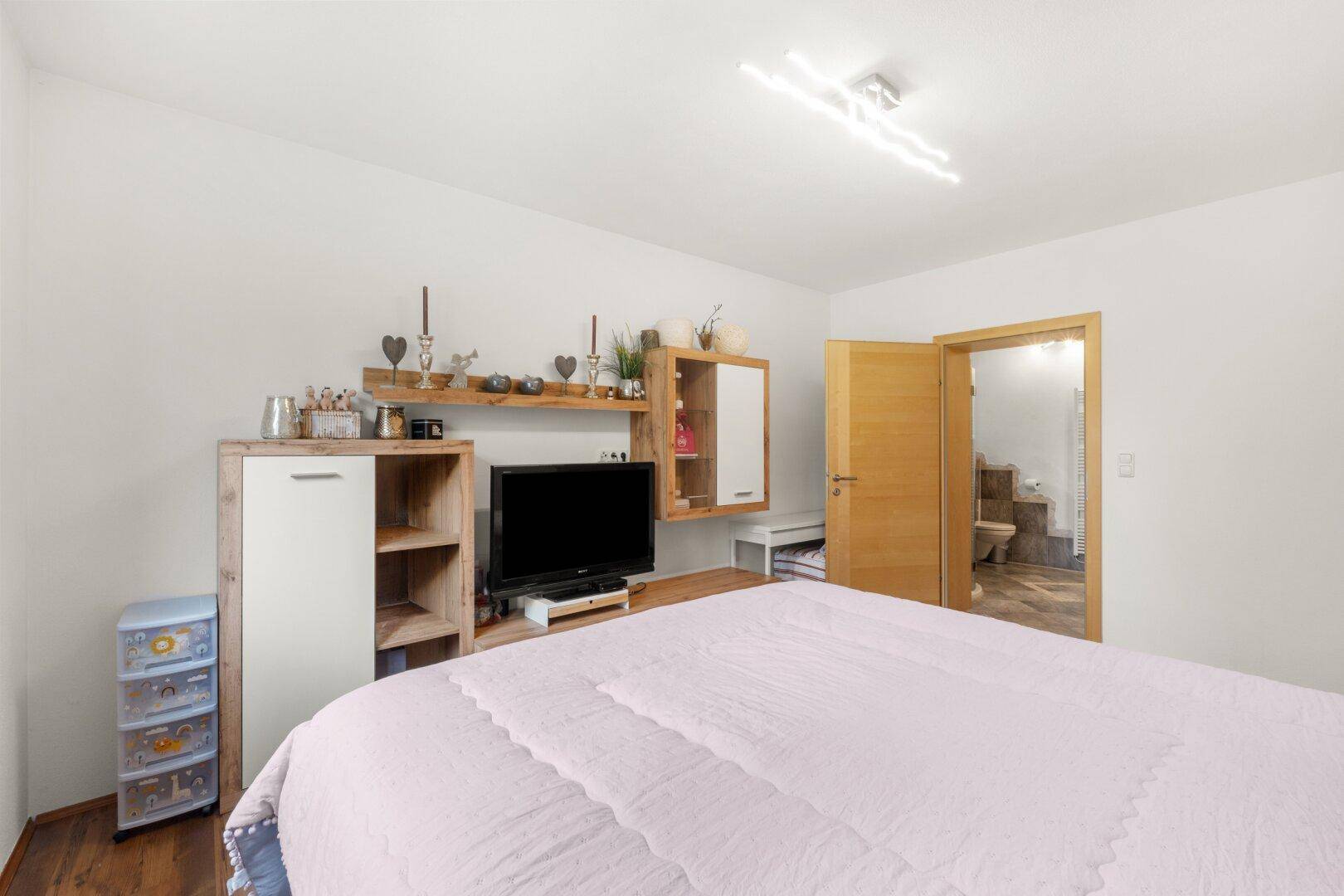 Gemütliches Schlafzimmer mit Doppelbett und direktem Zugang zu einem modernen Badezimmer.