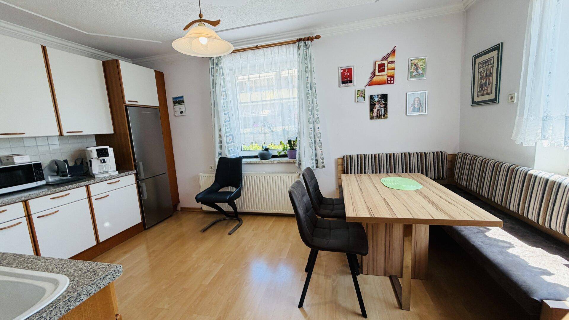 Essbereich in der Küche mit Eckbank, Holztisch und Fenster.