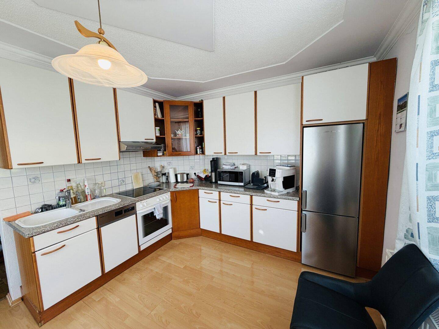 Traditionelle Küche mit weißen Schränken, Holzdetails und integrierten Geräten.