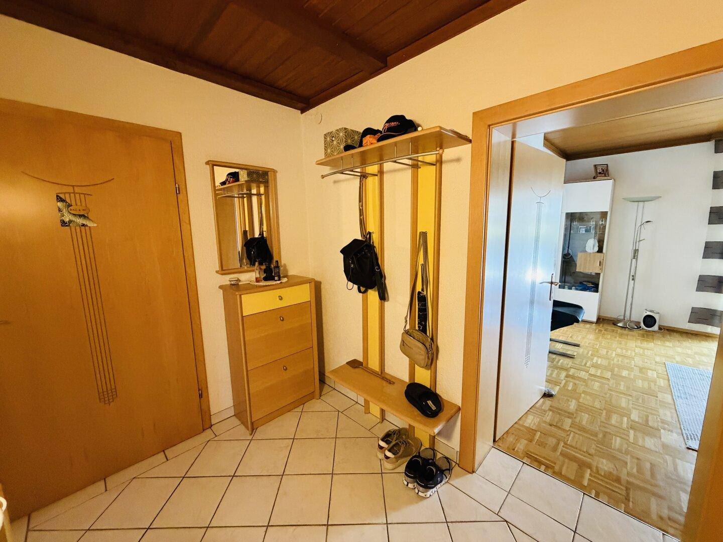 Gemütlicher Eingangsbereich mit Garderobe, Spiegel und Fliesenboden.