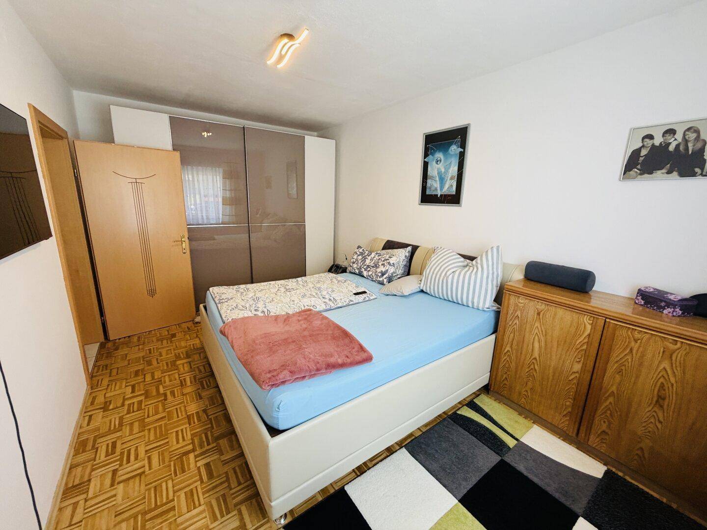 Schlafzimmer mit Doppelbett, Einbauschränken und Parkettboden.