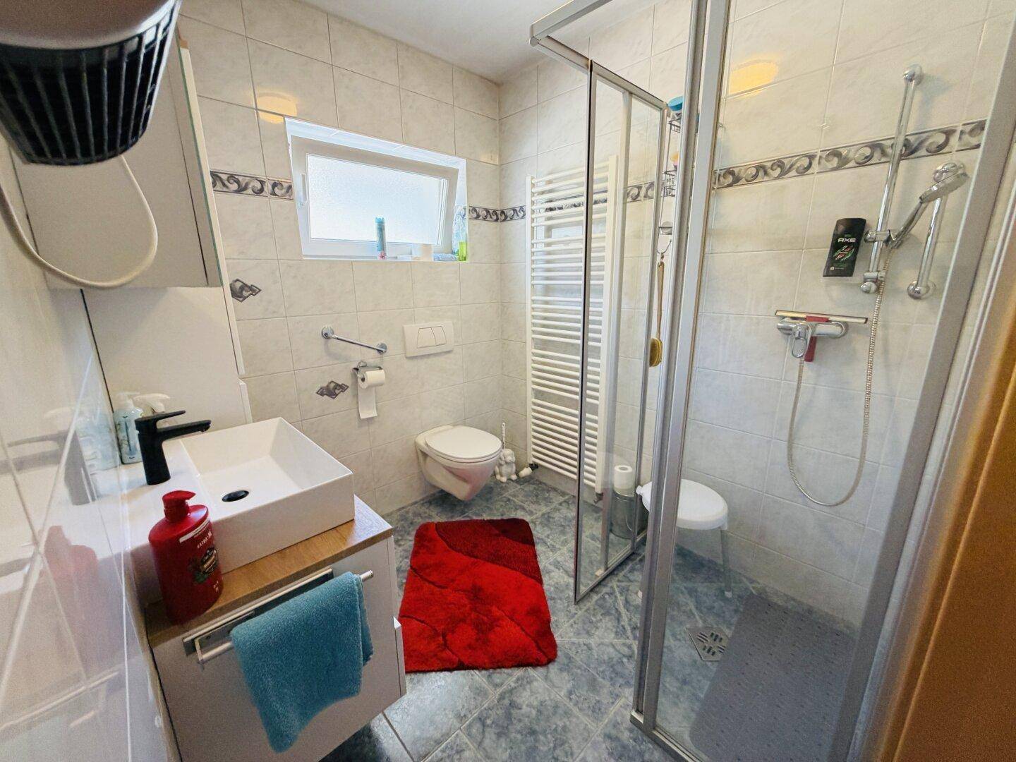 Modernes Badezimmer mit Dusche, Waschbecken und beheiztem Handtuchhalter.