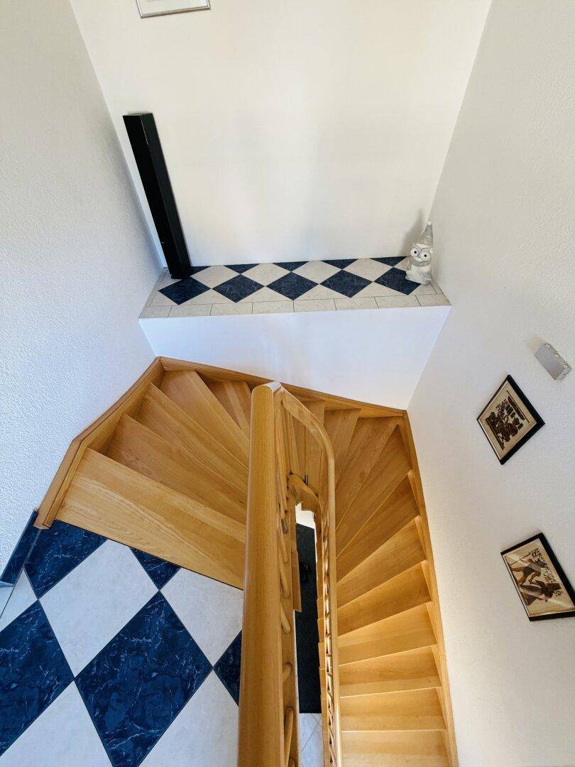 Wendeltreppe aus Holz mit dekorativen Fliesen und Blick nach unten.