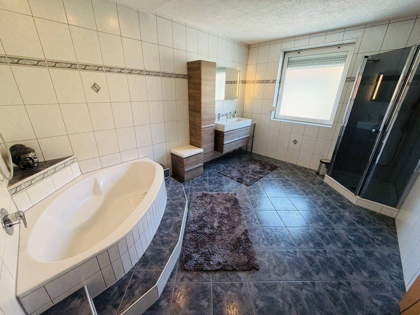 Großes Badezimmer mit Badewanne, Dusche, Doppelwaschbecken und Fenster.